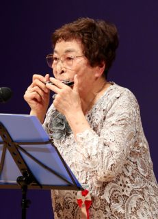 長崎市老人クラブ大会でハーモニカ演奏を披露する柴谷さん＝市民会館