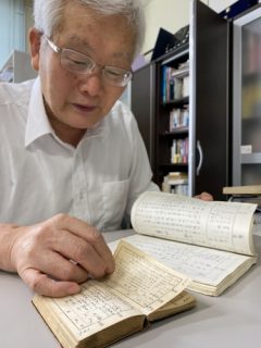 韓国人徴用工の「出張日記」（手前）と、それを書き写したノートを見比べる平野さん＝長崎市大黒町、平和活動支援センター