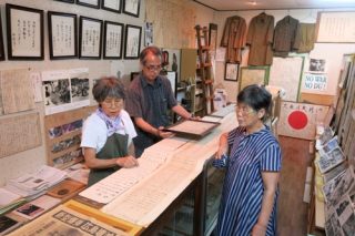 藤原さんが集めた資料を見詰める（左から）三女の朝比奈美知留さん、長男の藤原可能さん、長女の大舛久美絵さん＝佐世保市、天望庵