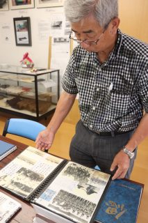 震洋隊員の遺品が並ぶ資料館で、写真を見つめる寺井さん＝川棚町